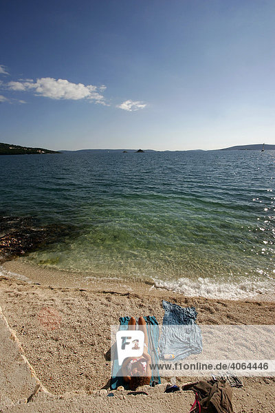 Frau beim Sonnenbaden am Strand bei Trogir  Kroatien  Europa