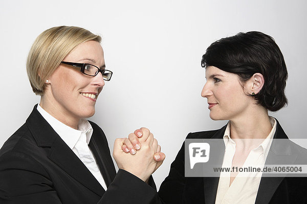 Zwei Frauen mit Händedruck und selbstbewusstem Blick