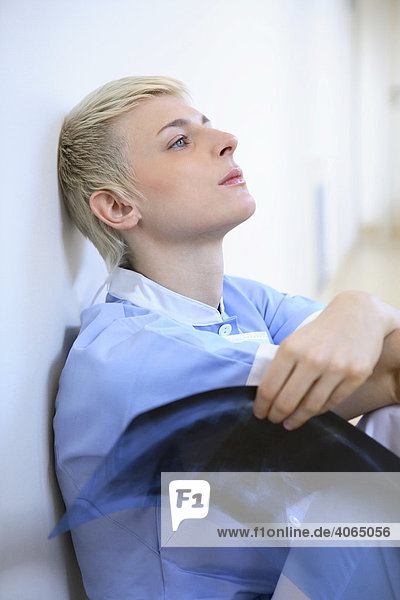 Übermüdete Krankenschwester mit Röntgenfilm in der Hand