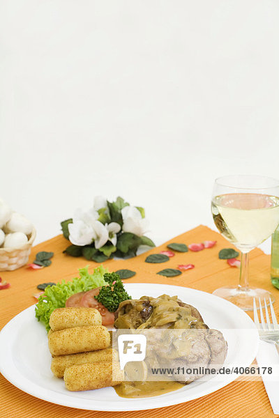 Schweinefiletmedaillons mit Champignons in Rahmsoße  Kartoffelkroketten  Weißwein und Dekoration