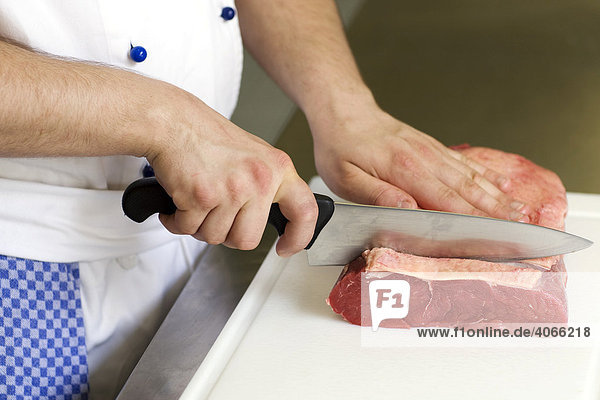 Koch schneidet Steaks aus einem Rinderroastbeef