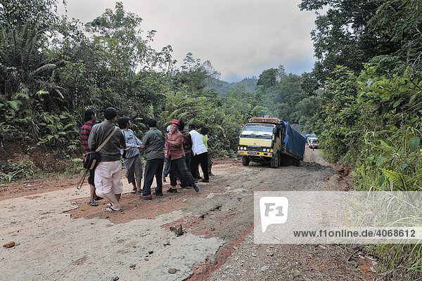 Menschen ziehen stecken gebliebenes Fahrzeug  Straße von Sintang nach Putussibau  West-Kalimantan  Borneo  Indonesien  Asien