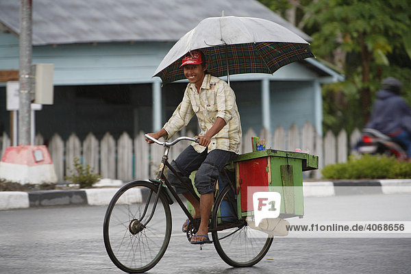 Mann  Fahrrad  Regen  Regenschirm  Pangkalan-Bun  Zentral Kalimantan  Borneo  Indonesien  Südostasien