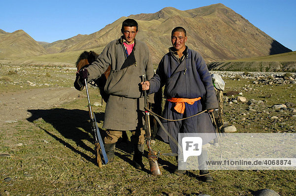 Nomaden  junge Männer in traditioneller Kleidung mit Gewehr stehen in der Steppe  Kharkhiraa  Mongolischer Altai bei Ulaangom  Uvs Aimag  Mongolei  Asien