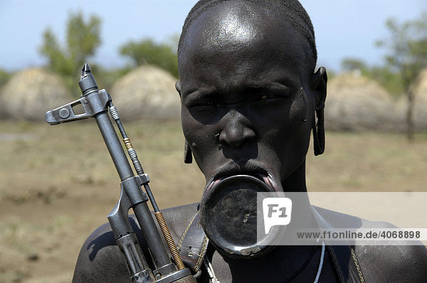 Woman with plate lip and a machine gun  Kalashnikov  from the Mursi tribe  Jinka  Ethiopia  Africa