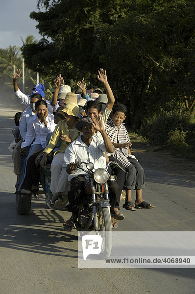 Enthusiastic people traveling on a crammed full motorikshaw  near Phnom Penh  Cambodia  Southeast Asia