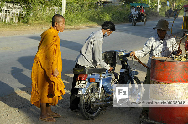 Motocycle driver with a monk at a primitive gas station  near Phnom Penh  Cambodia  Southeast Asia
