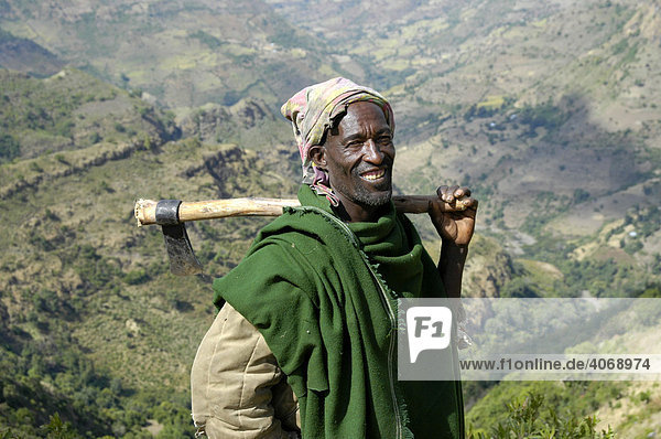 Bauer in grünem Umhang mit Hacke über der Schulter  Semien Mountains  Äthiopien  Afrika