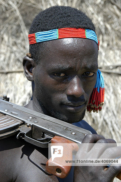 Karo tribesman wearing a colorful headband shouldering a rifle  portrait  Kolcho  South Omo Valley  Ethiopia  Africa