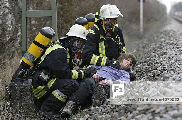 Feuerwehrleute mit Atemschutzgeräten helfen Verletztendarstellern bei einer Katastrophenschutzübung bei Poing  Bayern  Deutschland  Europa
