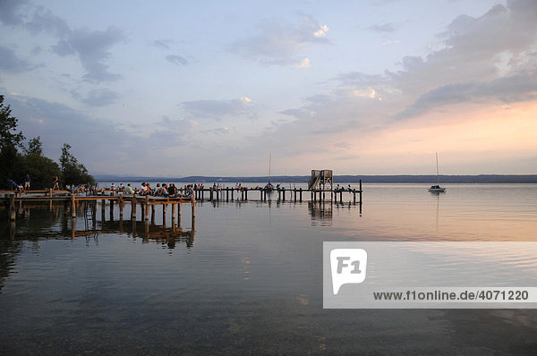 Wooden jetty with people at dusk  Herrsching  Ammersee Lake  Upper Bavaria  Germany  Europe