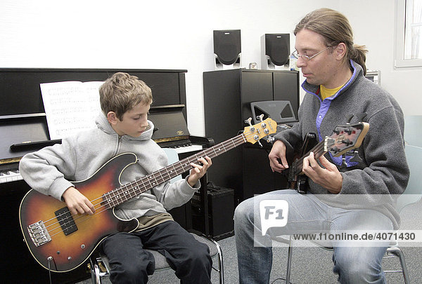 Youth  15  with his music teacher during a music lesson with a bass guitar in a private music school  Music Academy in Regensburg  Bavaria  Germany  Europe