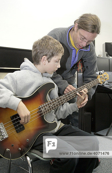 Youth  15  with his music teacher during a music lesson with a bass guitar in a private music school  Music Academy in Regensburg  Bavaria  Germany  Europe