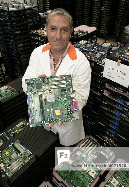 Computer production employee holding a mainboard towards the camera at the mainboard production of Fujitsu Siemens GmbH in Augsburg Bavaria Germany Europe