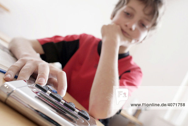 Ein Junge  10 Jahre alt  bei den Hausaufgaben mit einem Taschenrechner