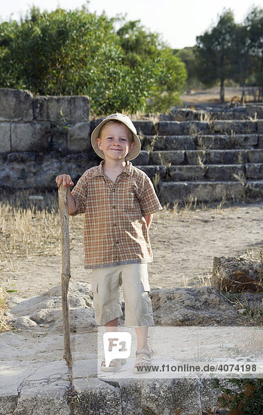 Boy  four years old  carrying a walking stick  in the archaeological excavation of Salamis in North Cyprus  Europe
