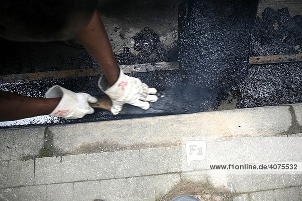 Straßenarbeiter verarbeitet heißen Asphalt
