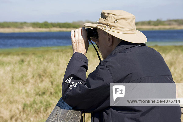 Mann sieht mit einem Fernglas auf einen Fluss  Tierbeobachtung