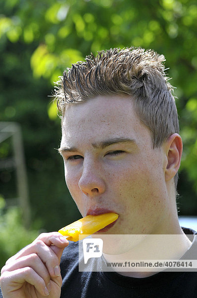 Jugendlicher isst ein Eis am Stiel