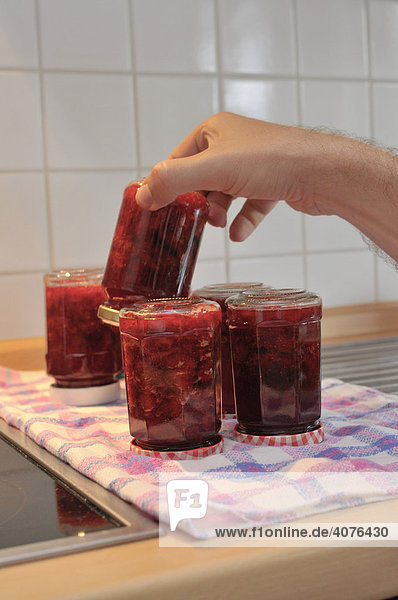 Hand und Gläser mit selbstgemachter Erdbeermarmelade
