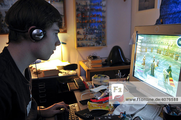 Jugendlicher sitzt im abgedunkelten Raum und spielt am Computer Online Rollenspiele