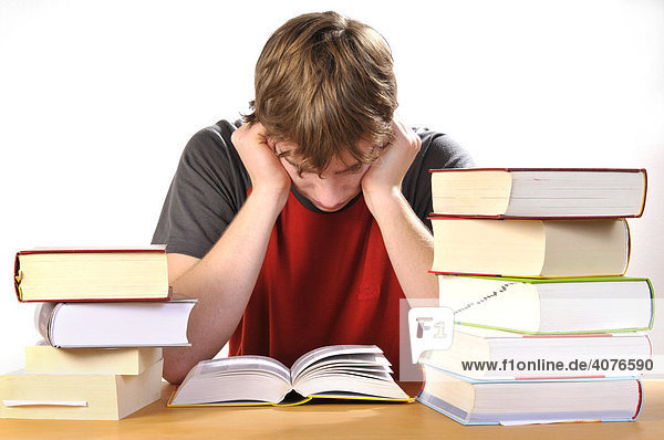 Jugendlicher sitzt genervt an seinen Hausaufgaben