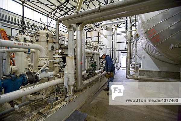 A worker checks gauges in a natural gas processing plant which removes carbon dioxide from the gas and vents it into the atmosphere  Mancelona  northern Michigan  USA