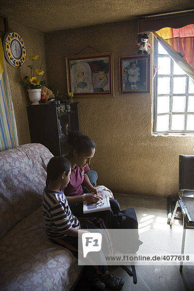 A woman reads to her son in the Pueblo Nuevo neighborhood of Nogales  Sonora  Mexico