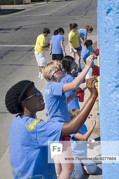 Freiwillige im Summer in the City Program malen eine Wandmalerei auf eine Mauer nahe des Detroit's Eastern Farmers Market Wochenmarkts  Detroit  Michigan  USA
