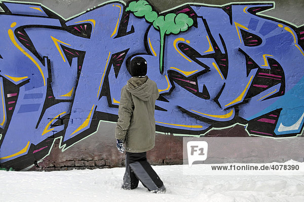 Ein achtjähriger Junge vor einer mit frischen Grafitti besprühten Wand an einem Bolzplatz in Köln  Nordrhein-Westfalen  Deutschland  Europa