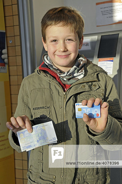 Ein achtjähriger Junge mit eigener EC-Karte am Geldautomat  Deutschland  Europa