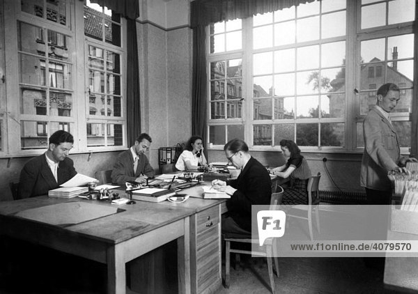 Historische Aufnahme  zwei Frauen und vier Männer arbeiten im Büro