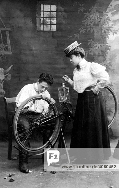 Historische Aufnahme  Mann repariert Fahrrad einer Dame  ca. 1912