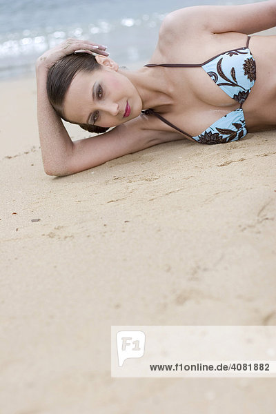 Junge Frau im Bikini liegt am Strand