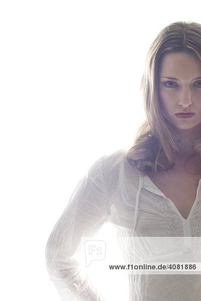 Junge Frau steht vor hell strahlendem weißem Hintergrund