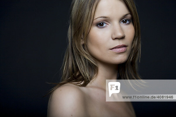 Woman looking into the camera  portrait in front of black