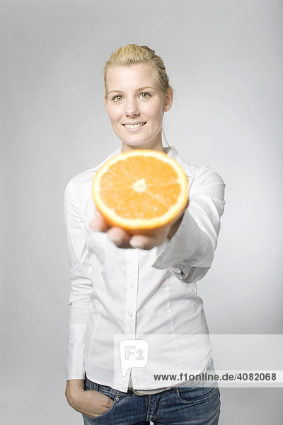 Blonde Frau hält eine aufgeschnittene Orange