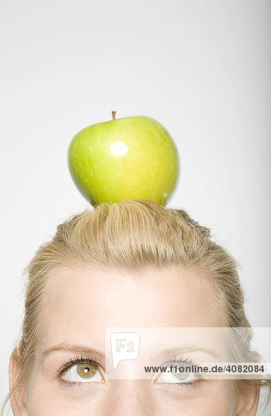 Junge blonde Frau mit grünem Apfel auf dem Kopf