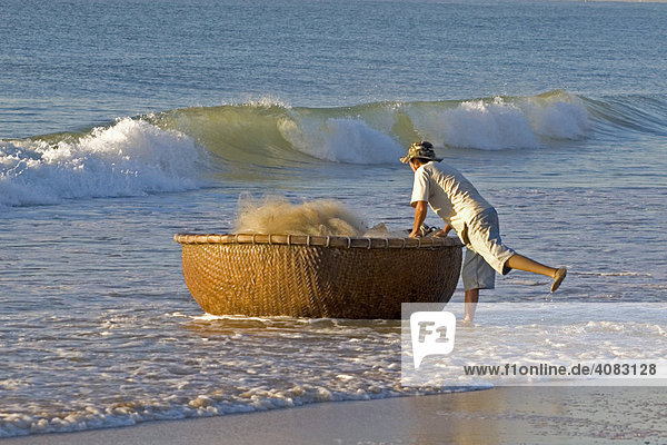 Ein Fischer bringt das traditionelle Rundboot an den Strand  Mui Ne  Vietnam  Asien