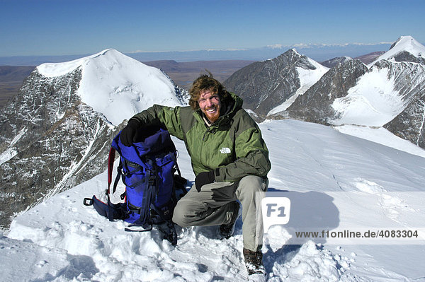 Mountaineer with his backpack on the snow covered summit of Turgen Uul Kharkhiraa Mongolian Altai near Ulaangom Uvs Aymag Mongolia