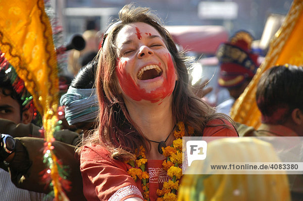 Junge westliche Frau mit roter Farbe im Gesicht lacht laut bei einer Party Fest auf der Straße Jaipur Holi Festival Rajasthan Indien