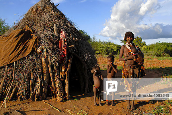 Mutter mit Kindern und Baby auf dem Arm vom Volk der Hamar vor typischer Hütte in der Savanne bei Turmi Äthiopien