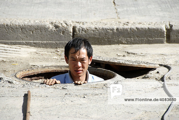 Chinesischer Arbeiter schaut aus einem Kanal Tsetang Tibet China