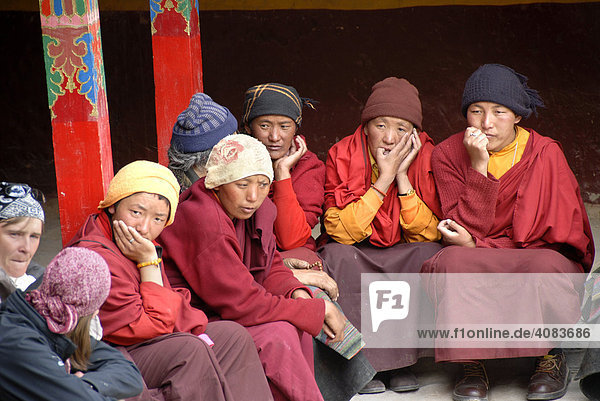 Tibetische Nonnen in roten Roben sitzen nebeneinander im Kloster Rongbuk Tibet China