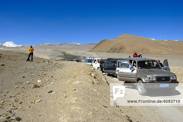Tourists at convoy of 4X4 off road vehicles on dirt road in Everest region Tibet China