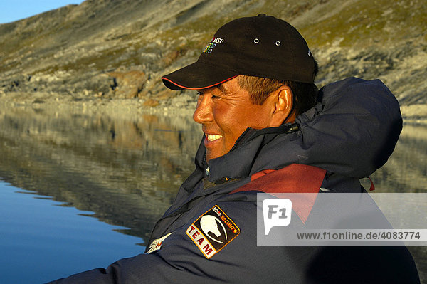 Portrait lächelnder Inuit Grönländer in Daunenjacke im Nagtivit Kangertivat Fjord Ostgrönland