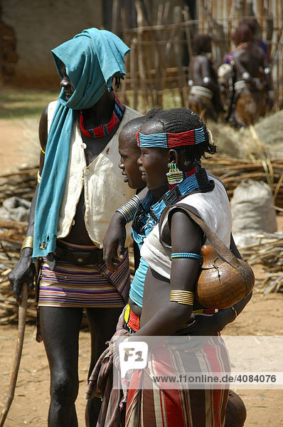 Bunt gekleideter Mann mit zwei jungen Frauen vom Volk der Hamar Markt von Dimeka Äthiopien