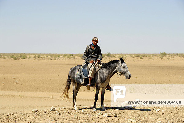 Nomads young rider on his horse in the sandy desert Kyzyl Kum Uzbekistan