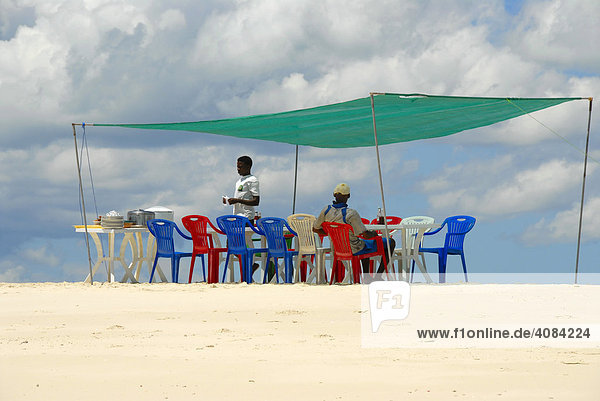 Table and chairs in the shade for lunch on a white sand bank near Kizimkazi Zanzibar Tanzania