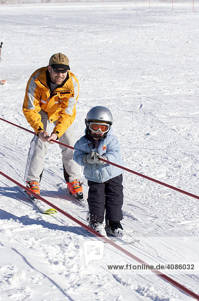 Boy 3 years is learning skiing with his father and is going by the ski lift MR